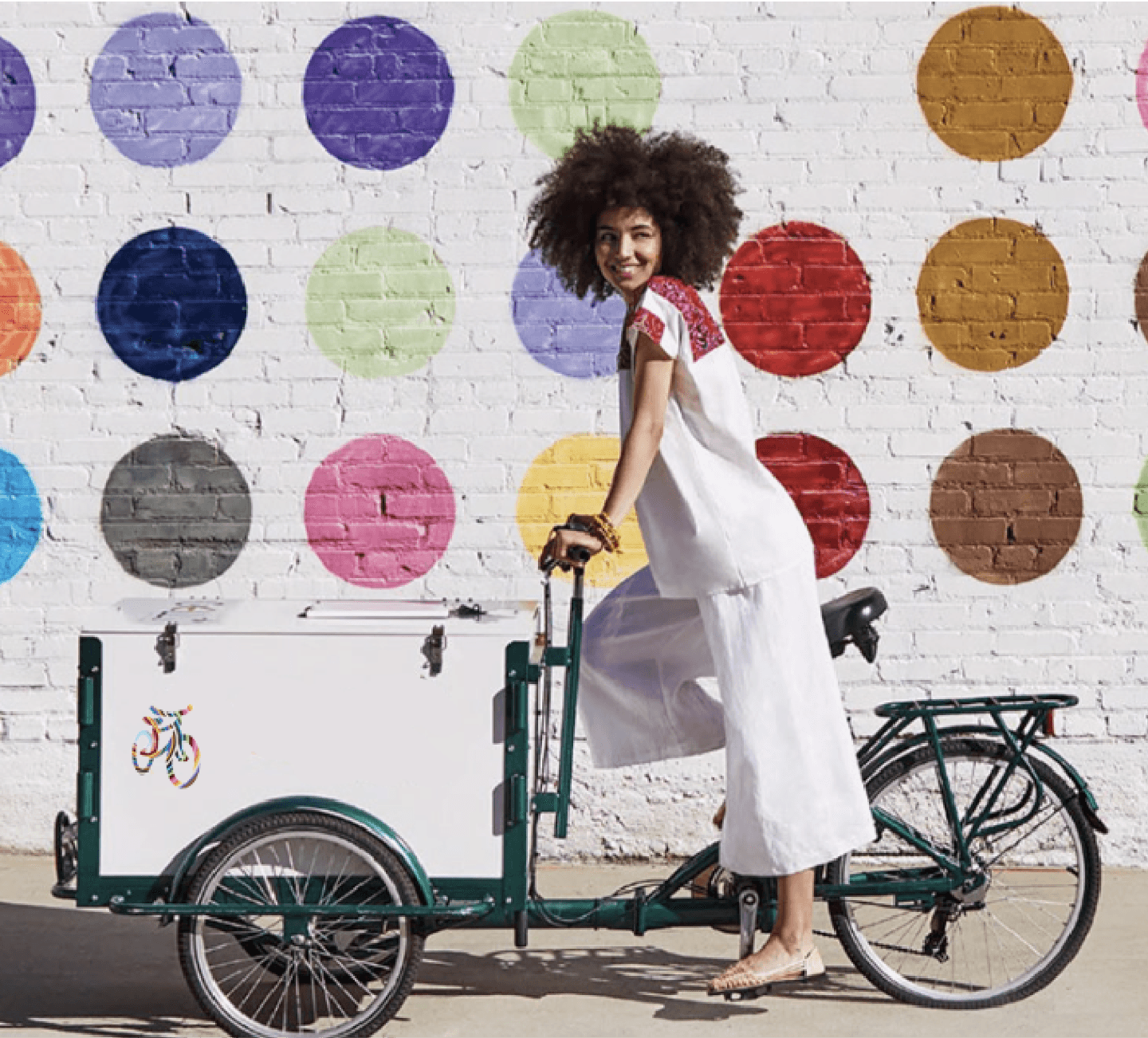 Woman riding a bike with a cart attachment.